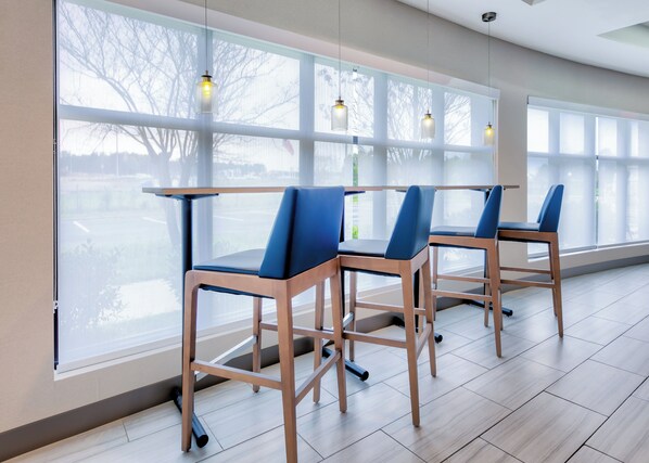 A modern interior with large windows, wooden chairs with blue cushions, and pendant lighting. - Holiday Inn Express Hotel & Suites Pell City by IHG (Pell City)