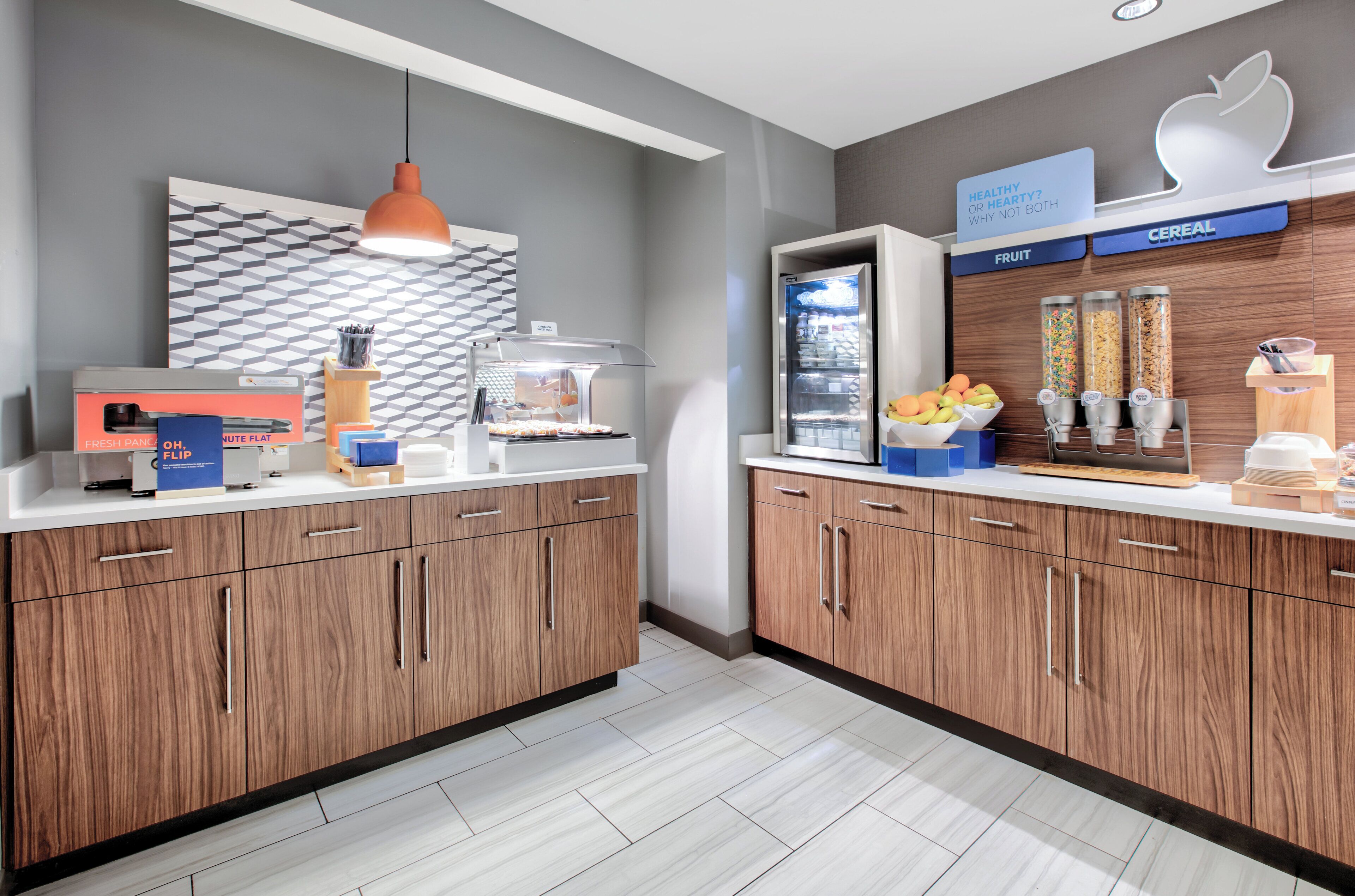 Een moderne keuken met houten kastjes, een fruitautomaat, een ontbijtgranenautomaat en een magnetron.