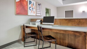 Un mostrador de recepción con una computadora, dos sillas y obras de arte enmarcadas en la pared.