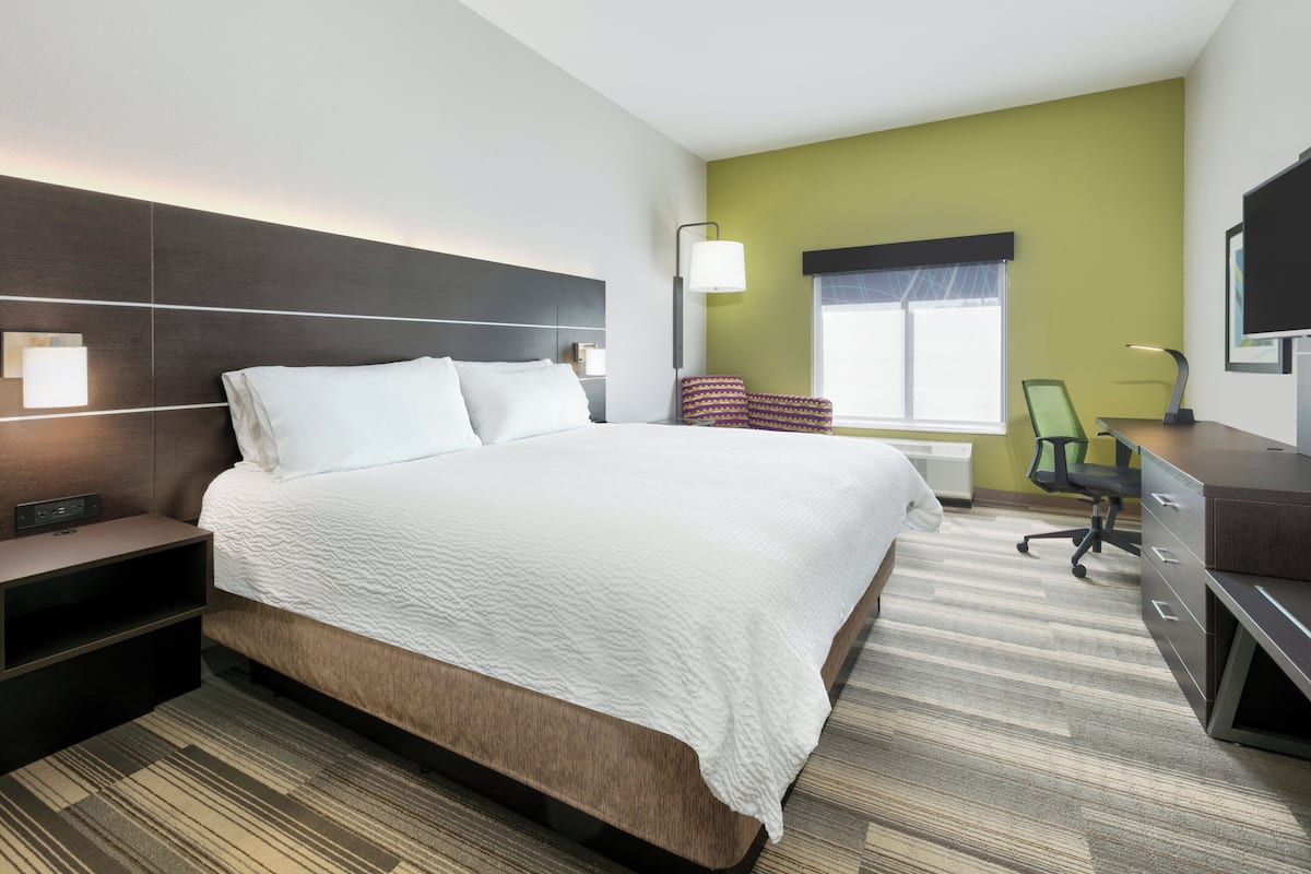A modern hotel room with a large bed, a desk, and a chair.