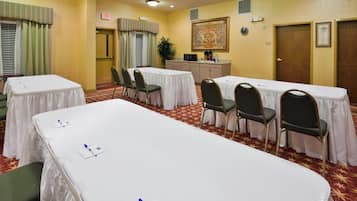 A conference room with tables and chairs, an exit sign, a clock, and a pantry sign.