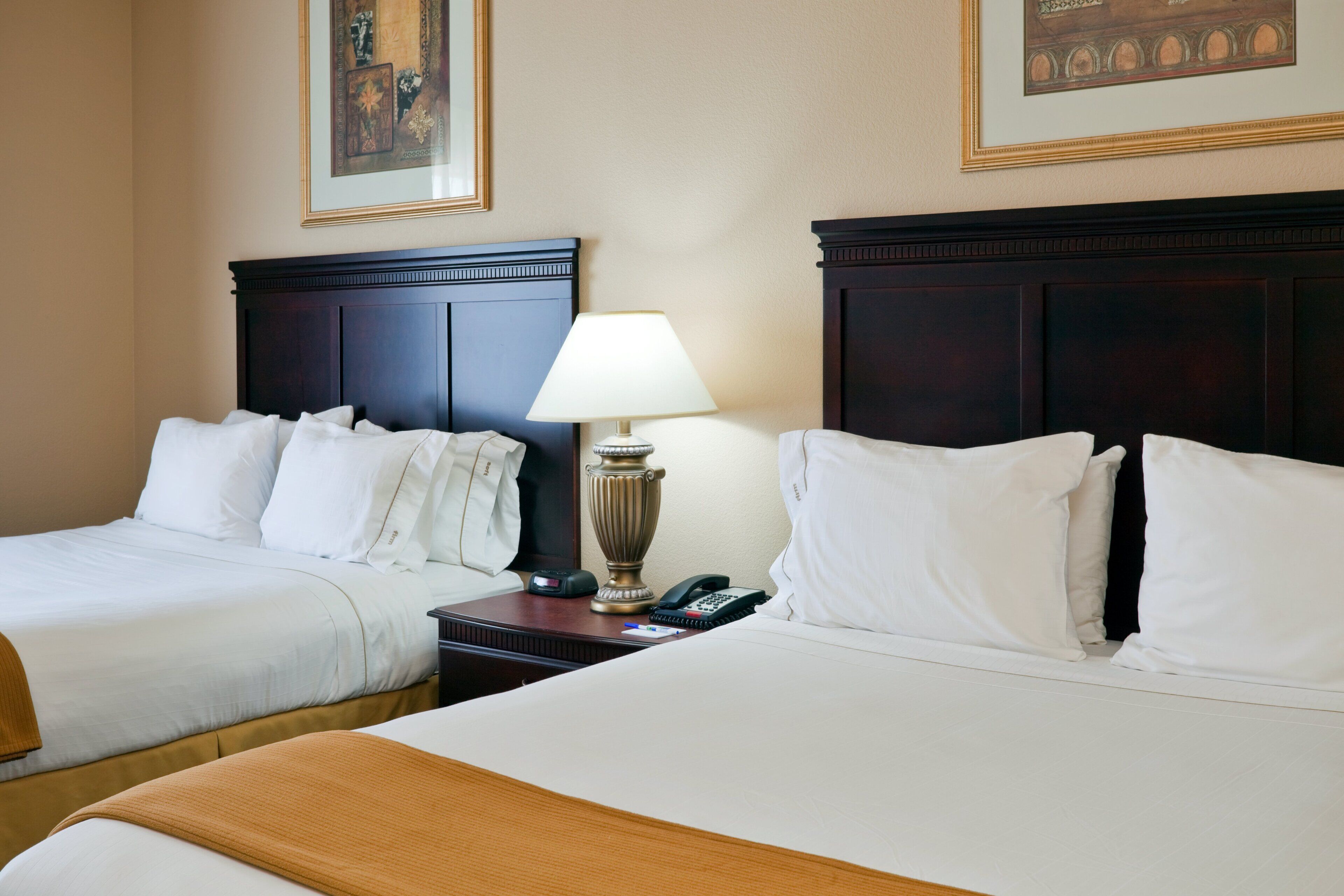 Une chambre d’hôtel avec deux lits, une table de chevet avec une lampe et un tableau au mur.