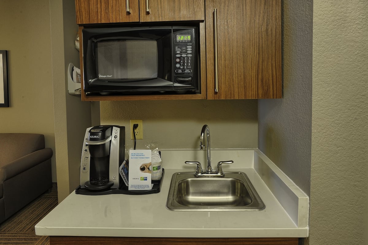 A kitchenette with a microwave, coffee maker, and sink.