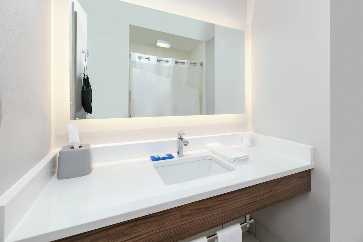 A modern bathroom with a white sink, a mirror, and a towel rack.