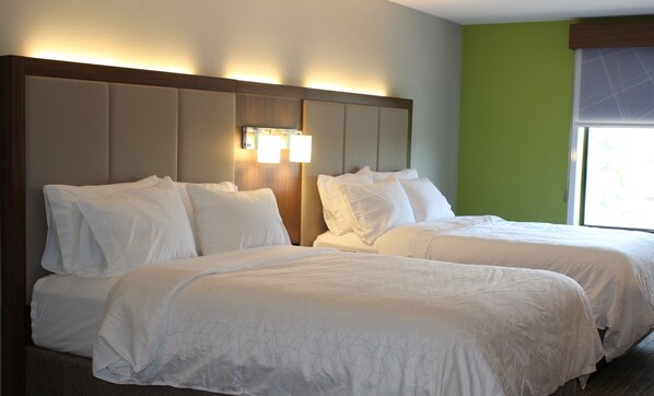 A hotel room with two beds, a headboard with built-in lighting, and a window with blinds. - Holiday Inn Express Forest City by IHG (Forest City)