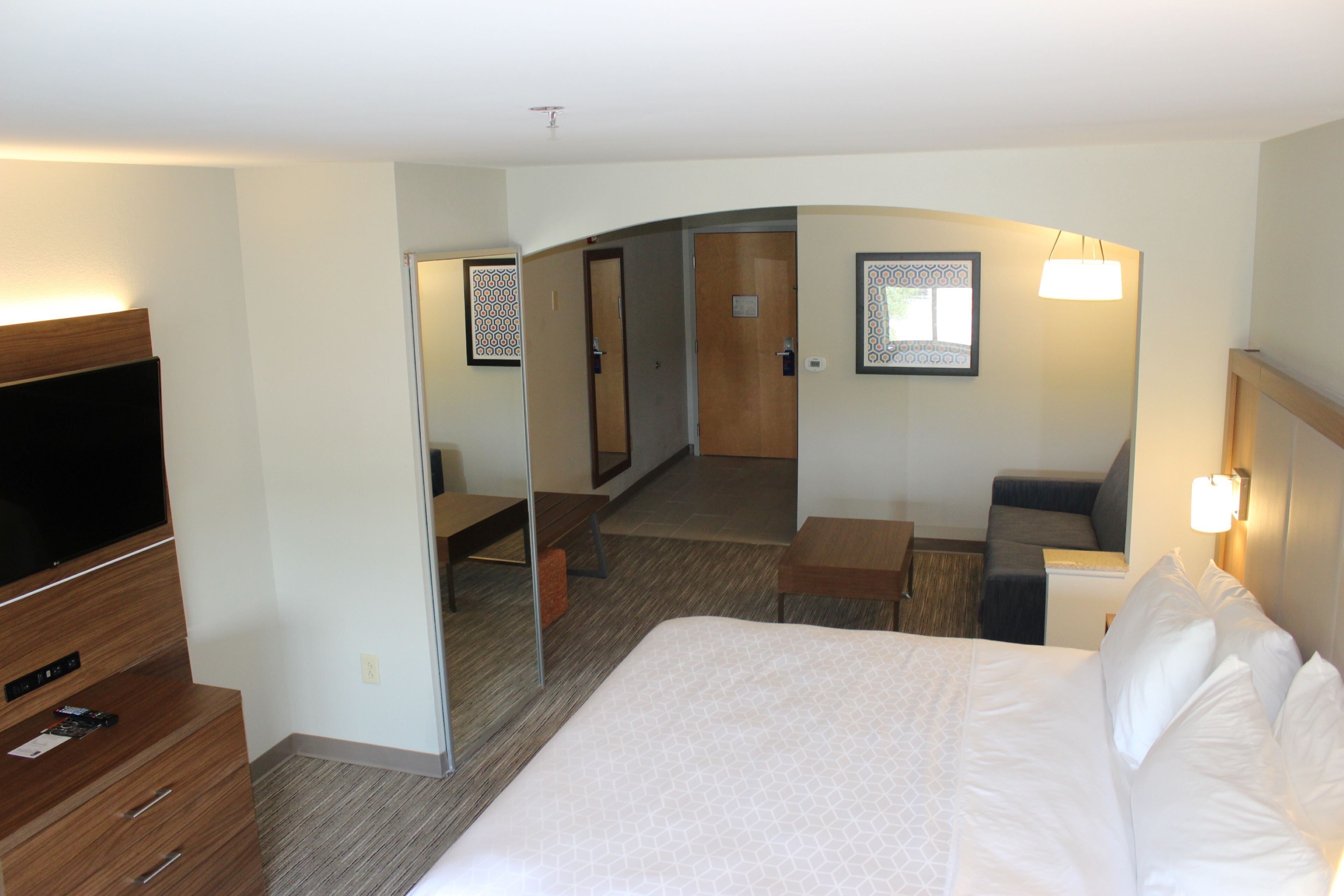 Une chambre d’hôtel avec un grand lit, une télévision, un bureau et un miroir.