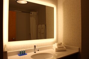 A bathroom with a large mirror, a sink, and a shower area. - Holiday Inn Express Forest City by IHG (Forest City)