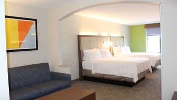 A hotel room with a bed, a sofa, a nightstand, and a wall art piece.