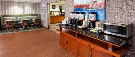 A hotel room with a kitchenette, a sofa, a dining table, and chairs.