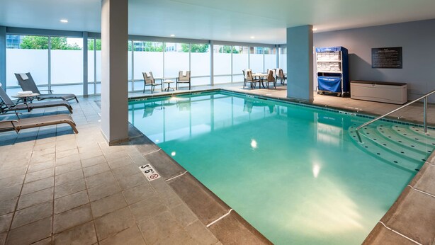 An indoor swimming pool with lounge chairs and a pool table, surrounded by large windows. - Hampton Inn & Suites St. Louis at Forest Park (St. Louis)