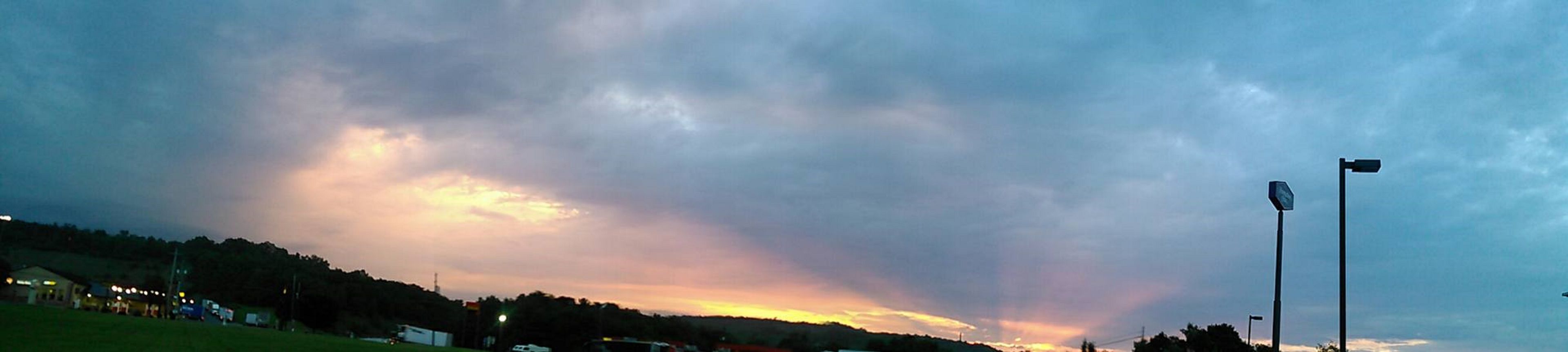 Un atardecer sobre un paisaje rural con una carretera y algunos edificios.