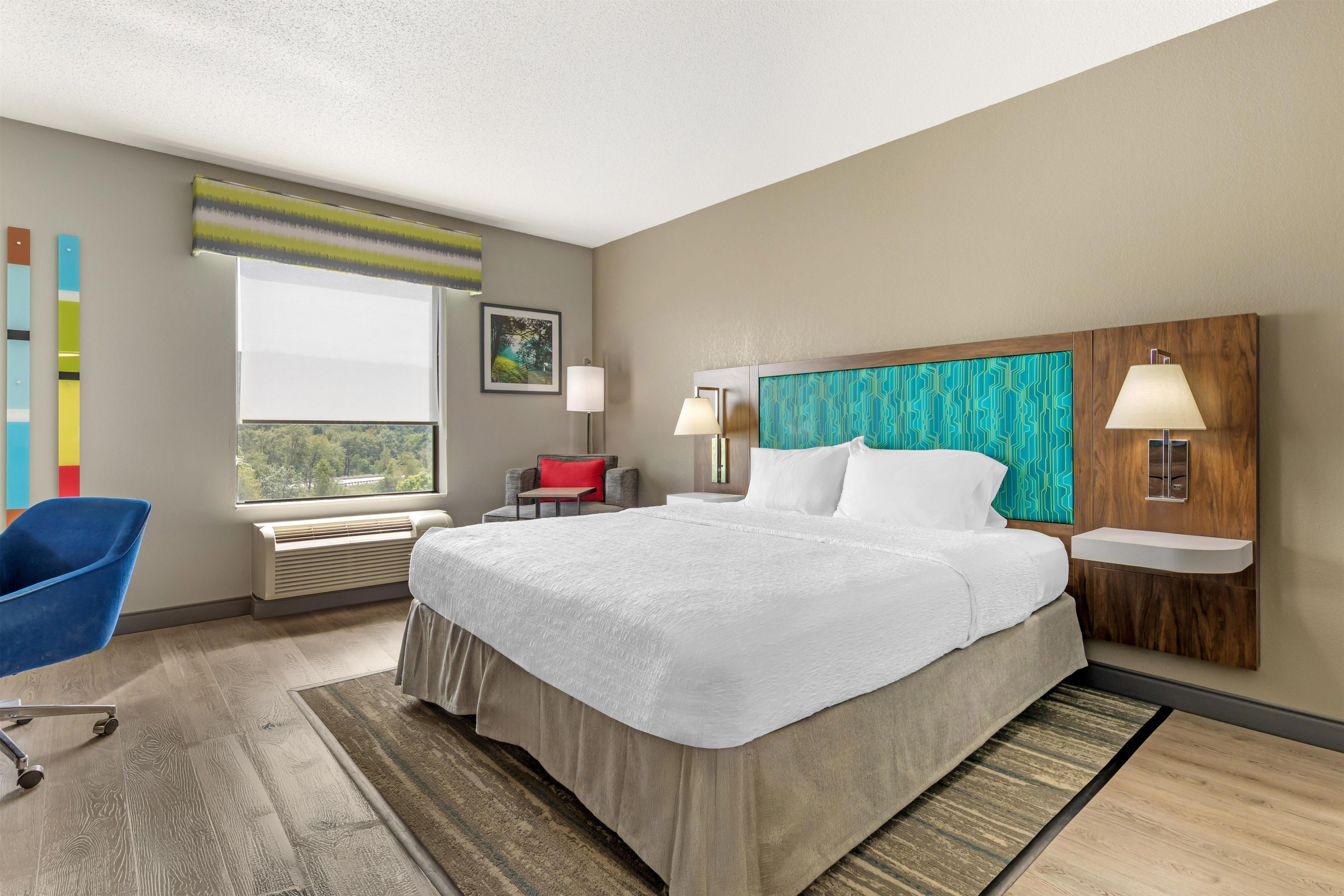 A hotel room with a large bed, a desk, a chair, and a window with a view.
