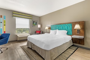 A hotel room with a large bed, a desk, a chair, and a window with a view.