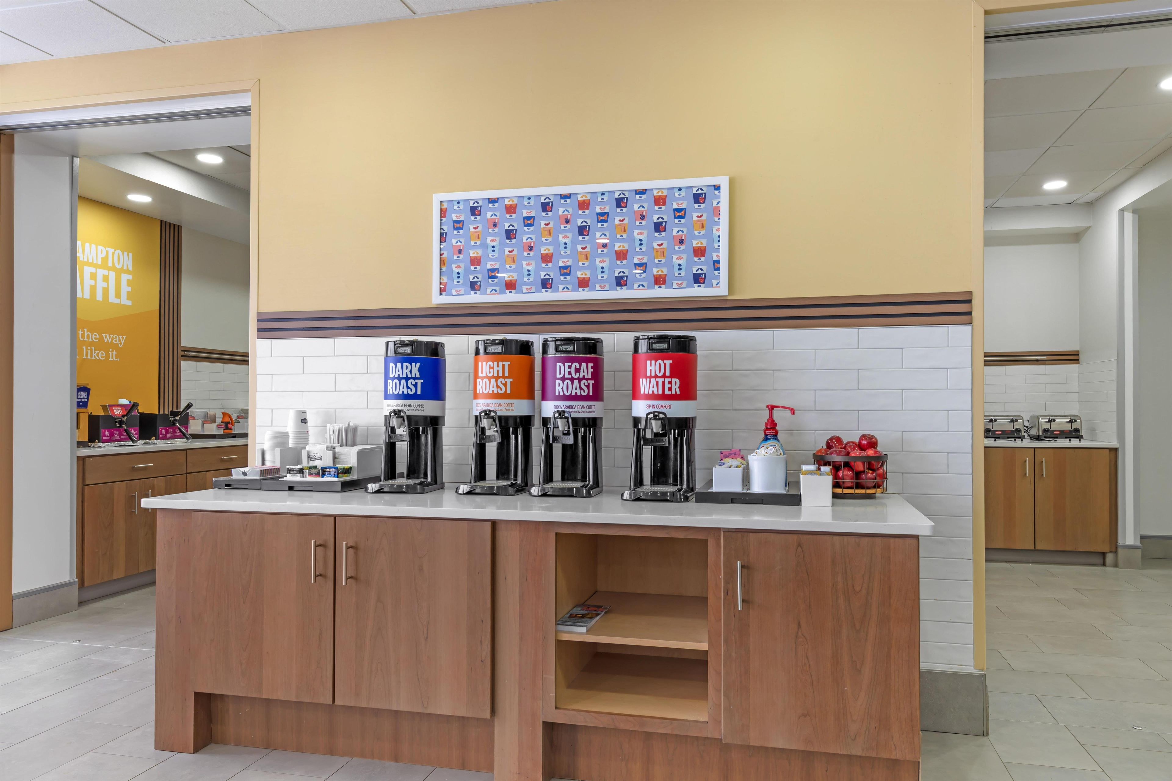 A coffee station with four dispensers labeled DARK ROAST, LIGHT ROAST, DECAF ROAST, and HOT WATER.