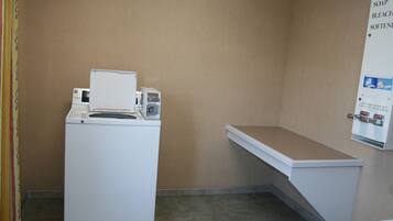 A laundry room with a washing machine and a wall-mounted soap dispenser.