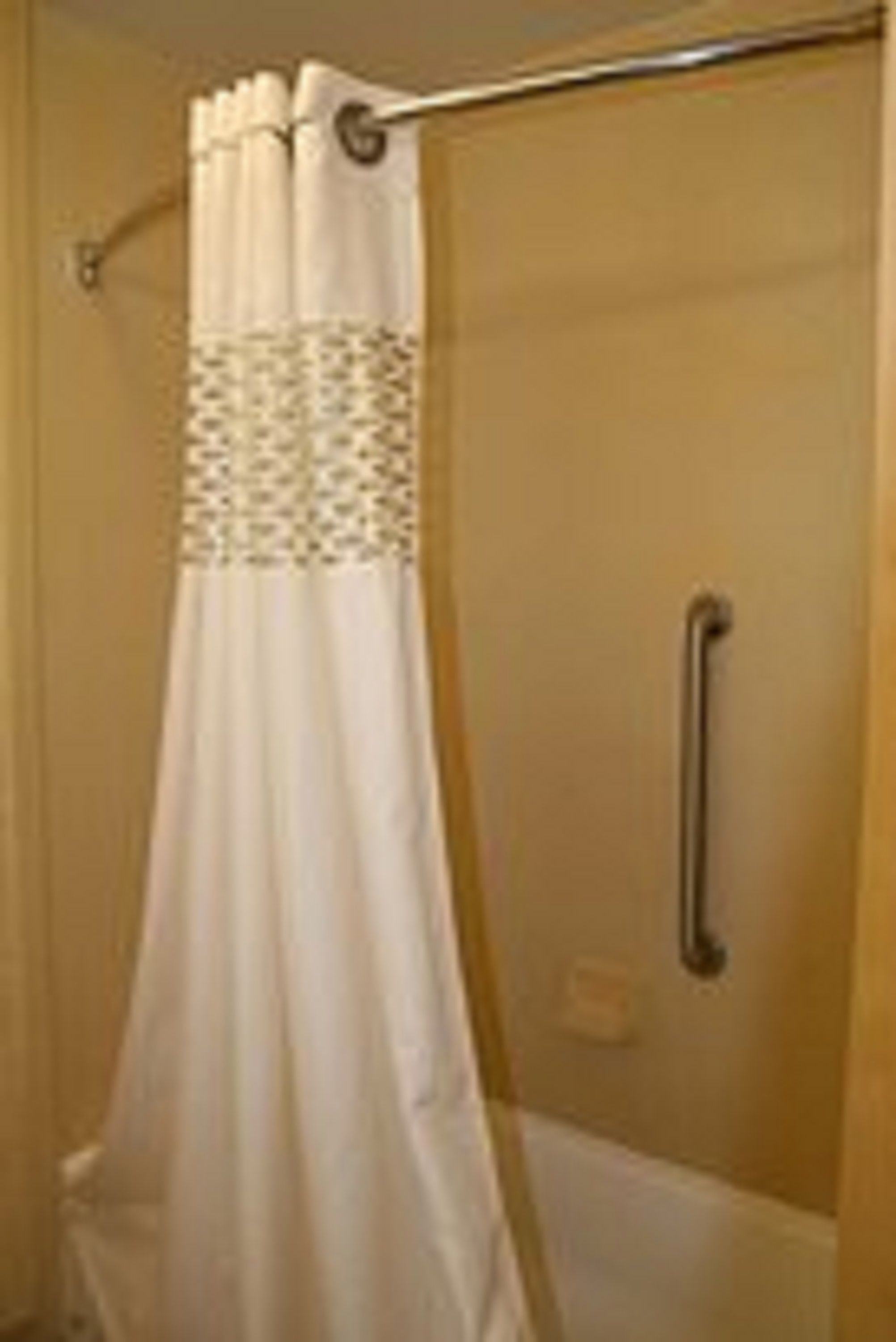 A bathroom with a shower curtain, a glass door, and a metallic handle.