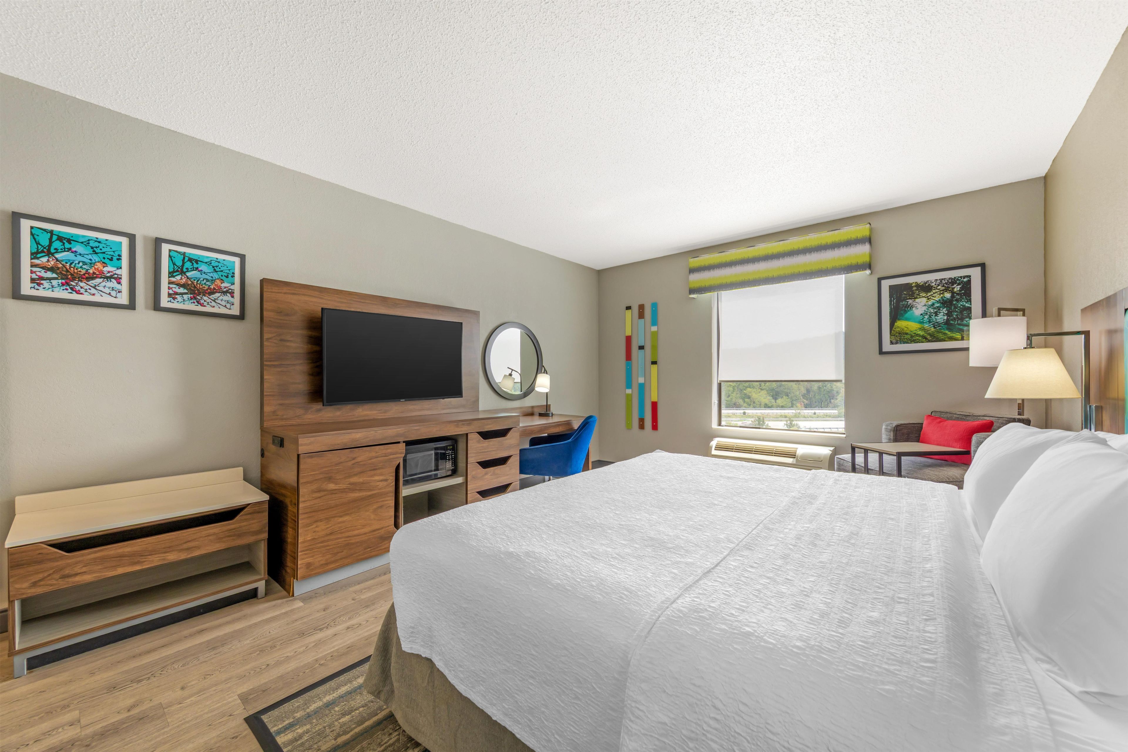 Ein Hotelzimmer mit Bett, Schreibtisch, Fernseher und Bildern an den Wänden.