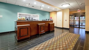 A reception area with a wooden counter, a framed picture, and a patterned rug. - Hampton Inn Pine Grove (Pine Grove)