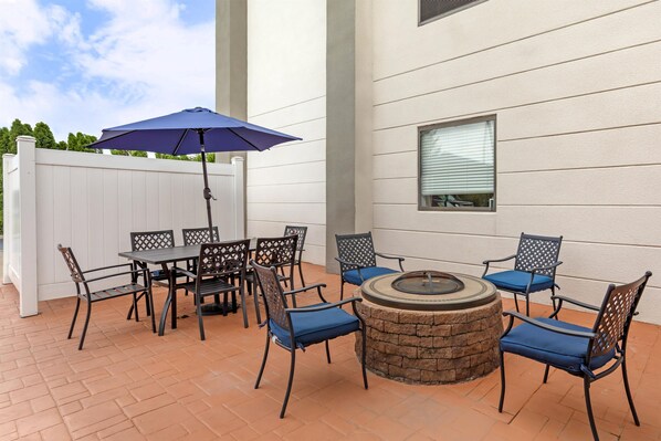 An outdoor patio with a table and chairs, a fire pit, and a white fence. - Hampton Inn Pine Grove (Pine Grove)