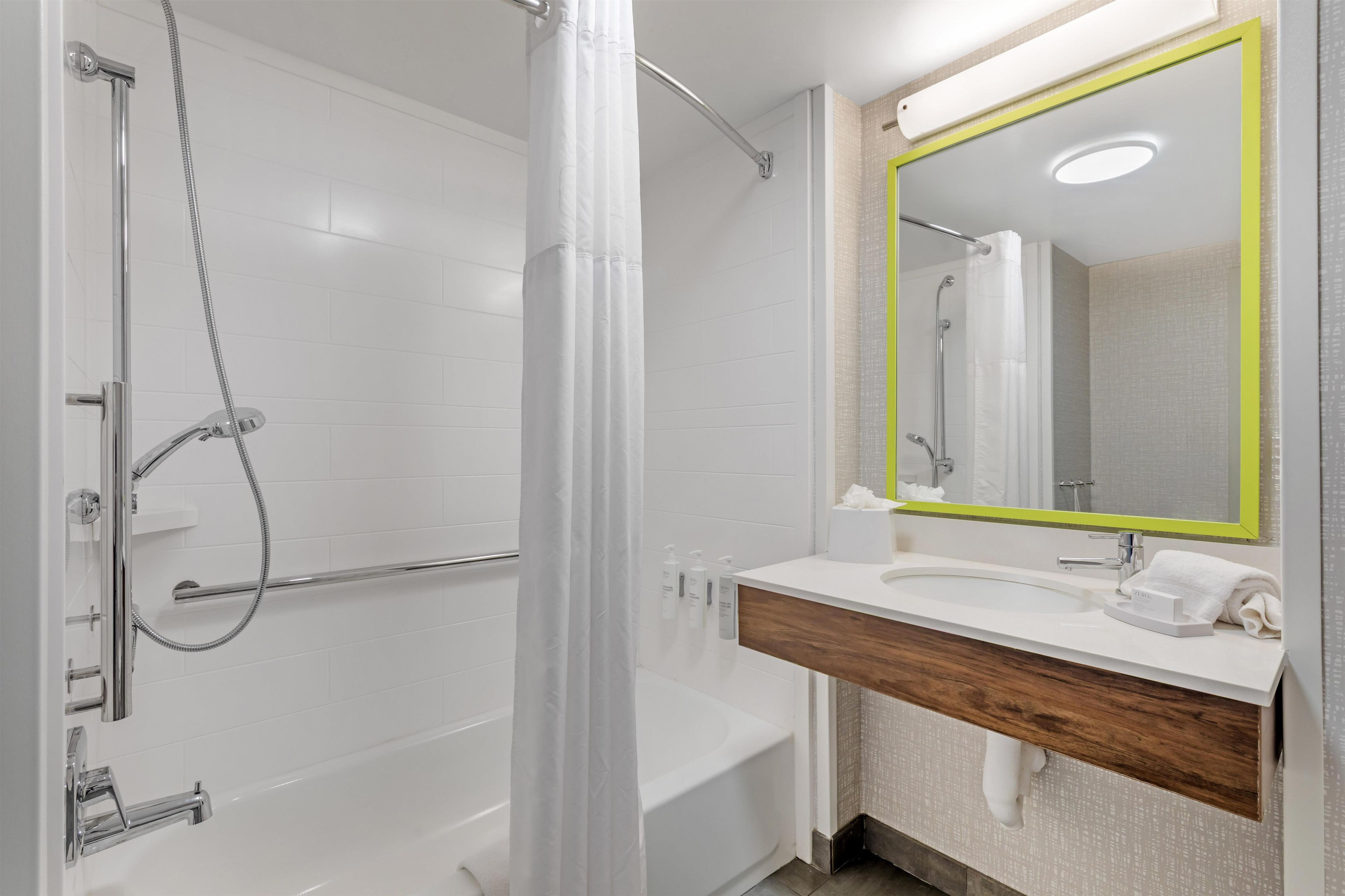 A modern bathroom with a glass shower enclosure, a white bathtub, and a vanity with a mirror.