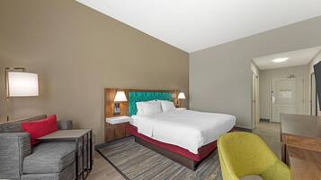 Una habitación de hotel con cama, escritorio, silla, sofá y lámpara.
