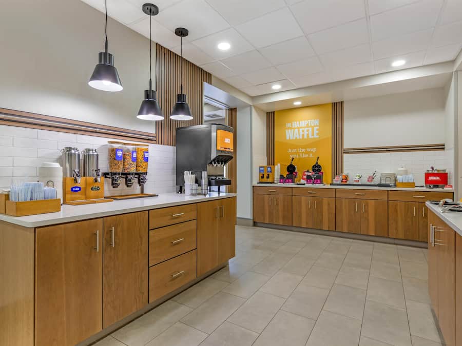 A modern kitchen with a central island, built-in appliances, and a branded waffle station.