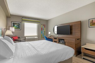Una habitación de hotel con cama, escritorio, televisor y ventana.