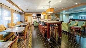 A hotel lobby with a long counter, multiple seating areas, and a television screen. - Hampton Inn Pine Grove (Pine Grove)