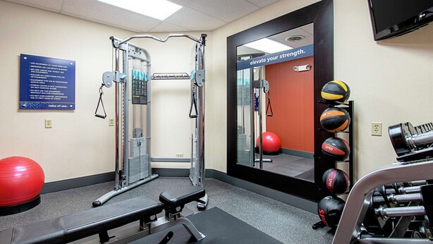 A gym with exercise equipment, a red exercise ball, and a mirror reflecting the room. - Hampton Inn Pine Grove (Pine Grove)
