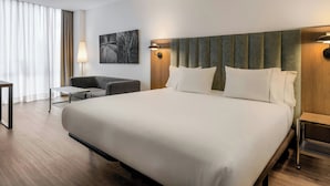 A hotel room with a large bed, a desk, a chair, and a wall-mounted lamp. - AC Hotel La Finca by Marriott (Pozuelo de Alarcon)