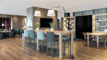 Una cocina moderna con una isla central, taburetes de bar, iluminación colgante y un televisor integrado.