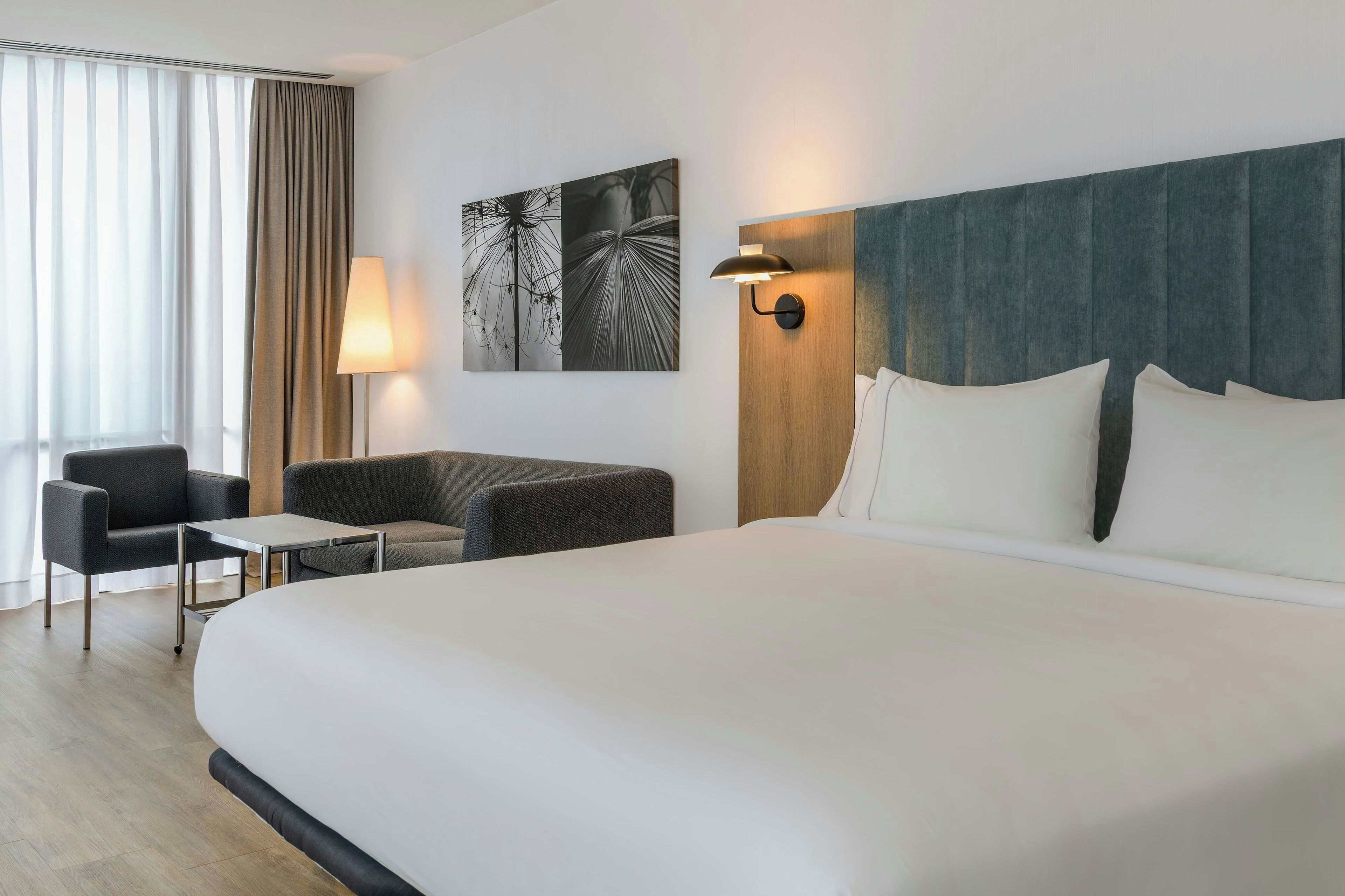Een hotelkamer met een groot bed, een bank, een kleine tafel en een lamp.