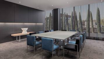 A modern conference room with a large table, blue chairs, and a bench.