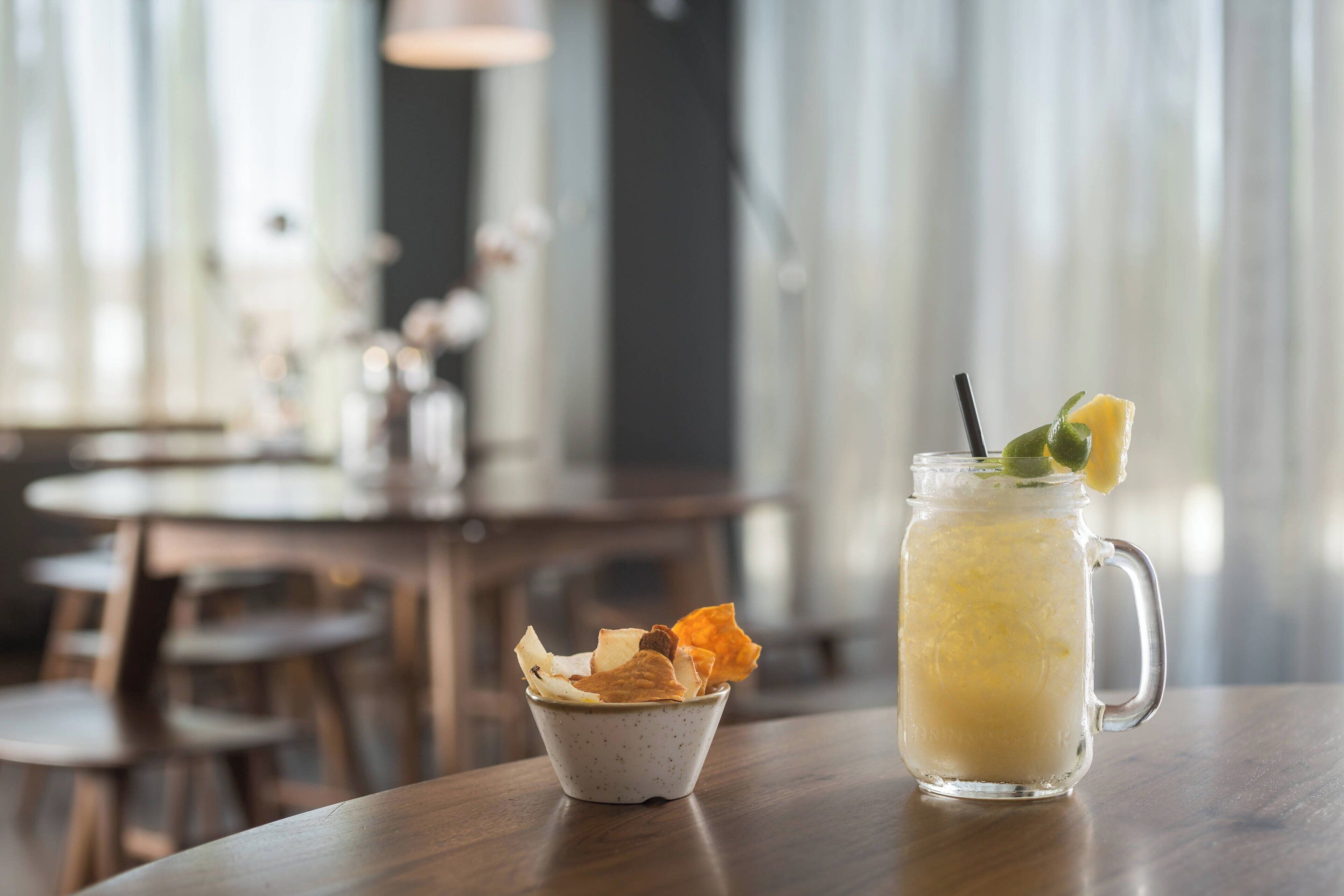 Un verre à boire avec une paille et une tranche de citron, posé sur une table en bois dans un restaurant.