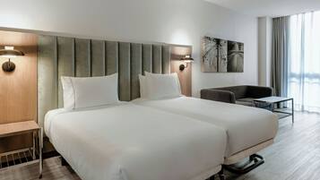 A hotel room with two beds, a desk, a chair, and a table.