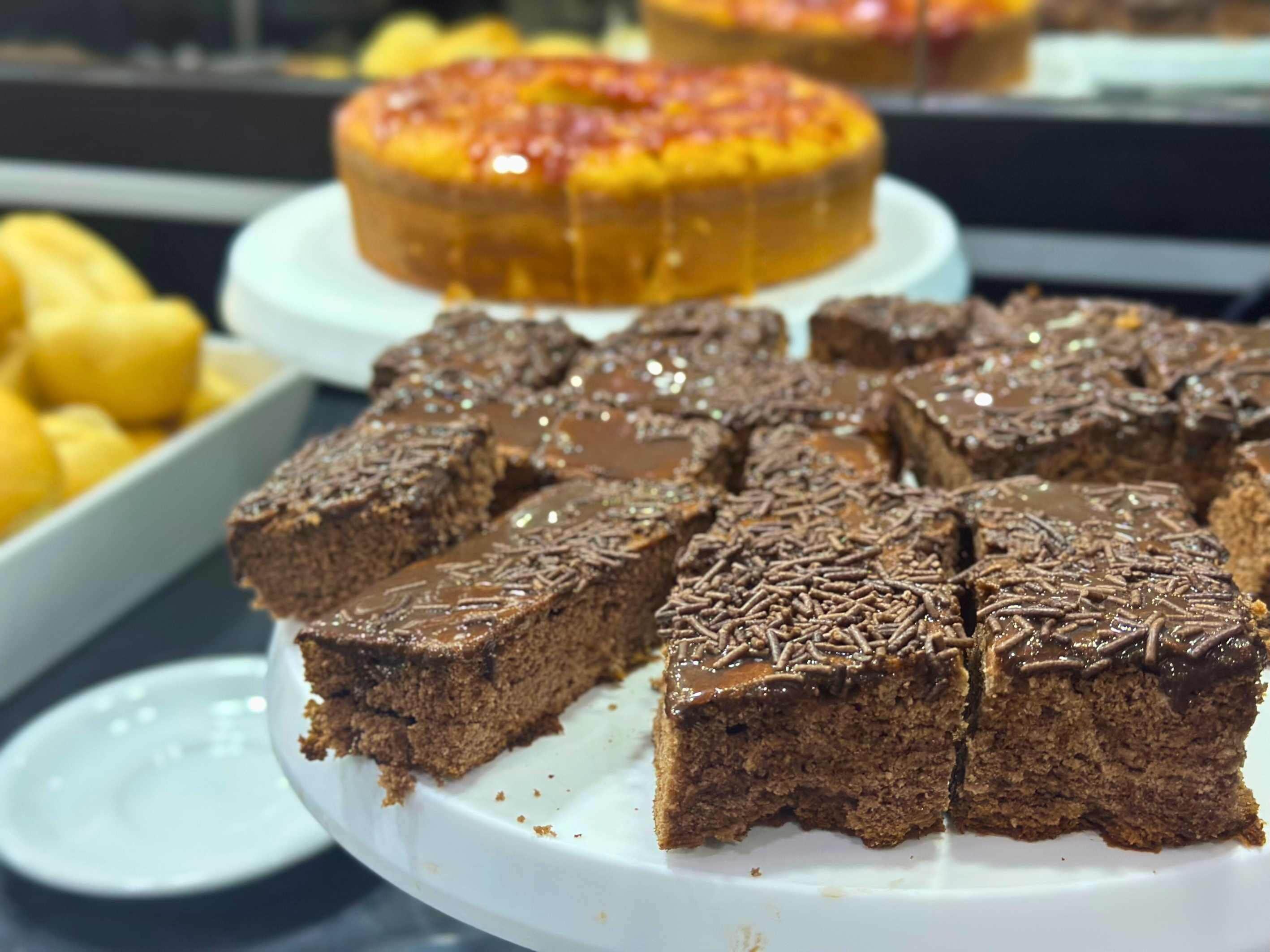 A dessert display with brownies and a cake.