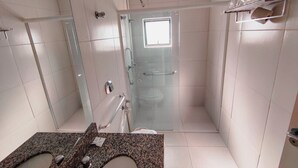 A bathroom with a glass shower enclosure, a vanity with a granite countertop, and a towel rack. - Granville Hotel (Curitiba)