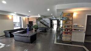 A lobby with a seating area, a snack bar, and a staircase. - Granville Hotel (Curitiba)
