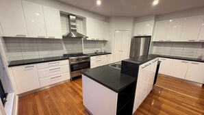 Una cocina moderna con armarios blancos, encimera negra, electrodomésticos de acero inoxidable y suelo de madera.