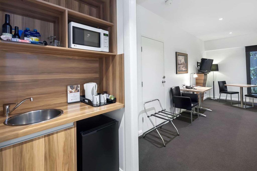 A modern kitchen with a microwave, sink, and coffee maker, a dining area with chairs and a table, and a view of the outdoors.