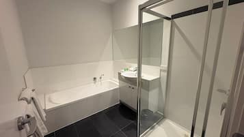 A modern bathroom with a bathtub, a glass-enclosed shower, and a sink.