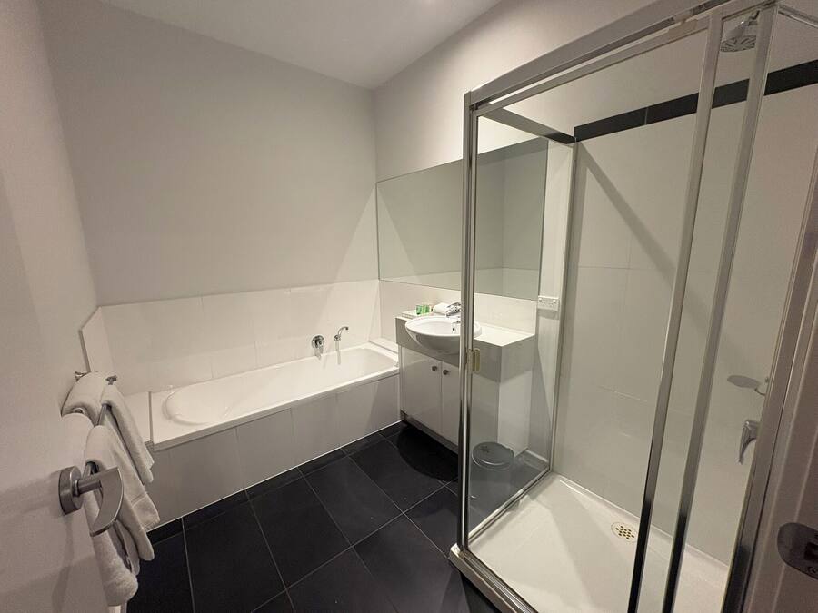 A modern bathroom with a bathtub, a glass-enclosed shower, and a sink.