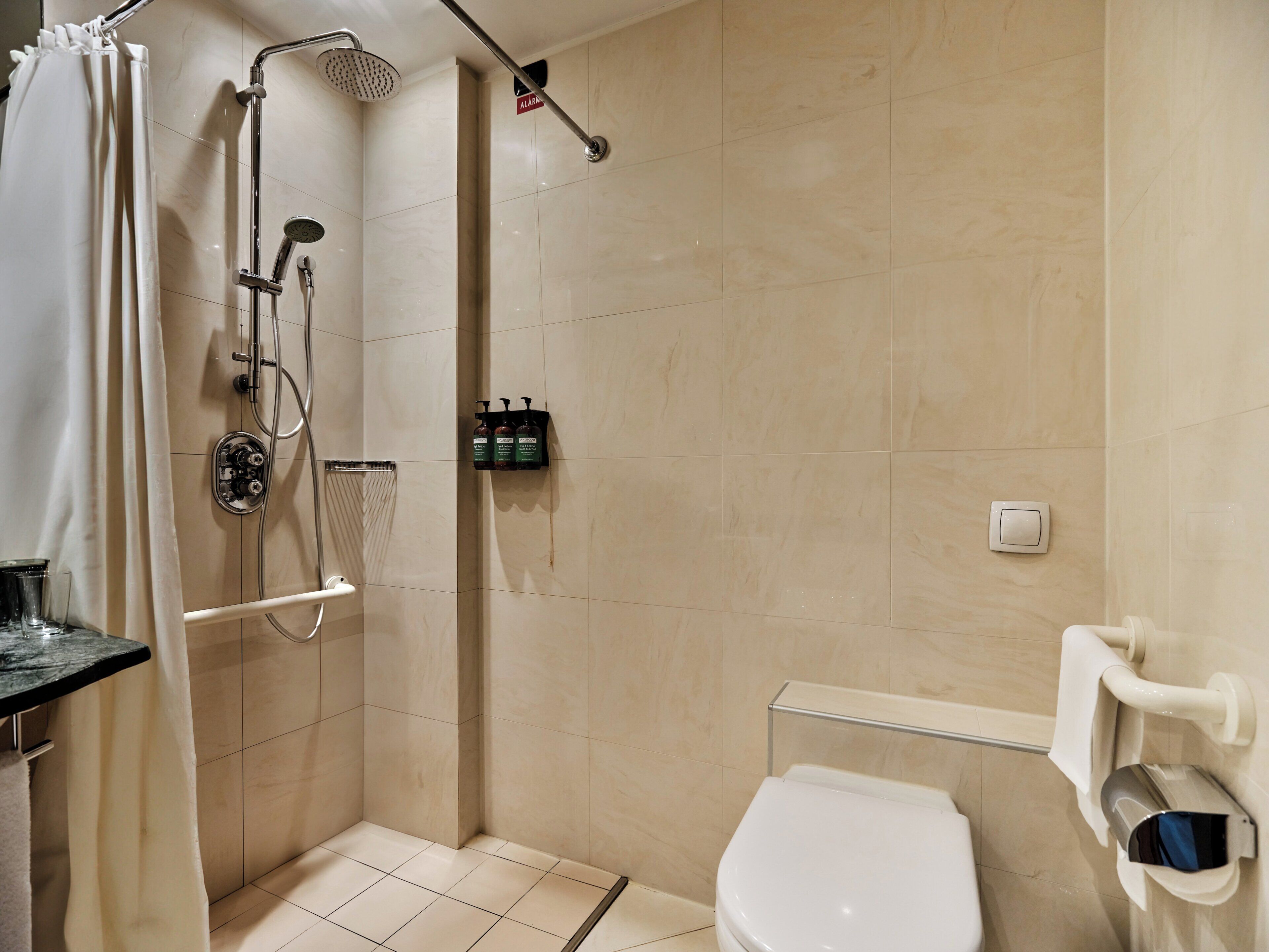 A bathroom with a shower, toilet, and a towel rack.