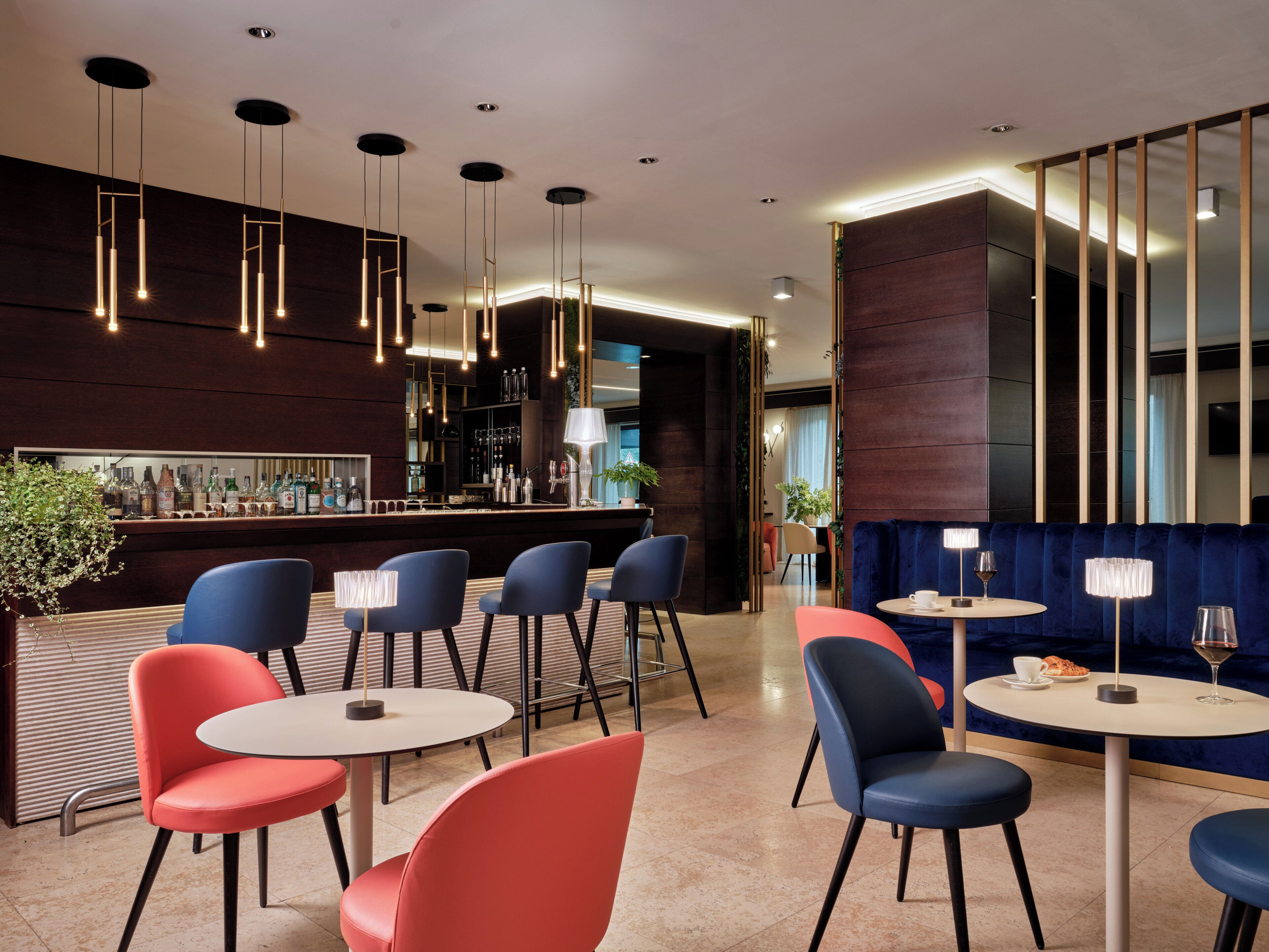 A modern bar area with multiple seating options, including round tables and chairs, and a bar counter with various bottles.