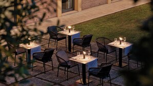 An outdoor patio with tables and chairs, some with candles, set against a brick wall. - Crowne Plaza Milan - Malpensa Airport by IHG (Somma Lombardo)