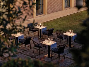 An outdoor patio with tables and chairs, some with candles, set against a brick wall. - Crowne Plaza Milan - Malpensa Airport by IHG (Somma Lombardo)