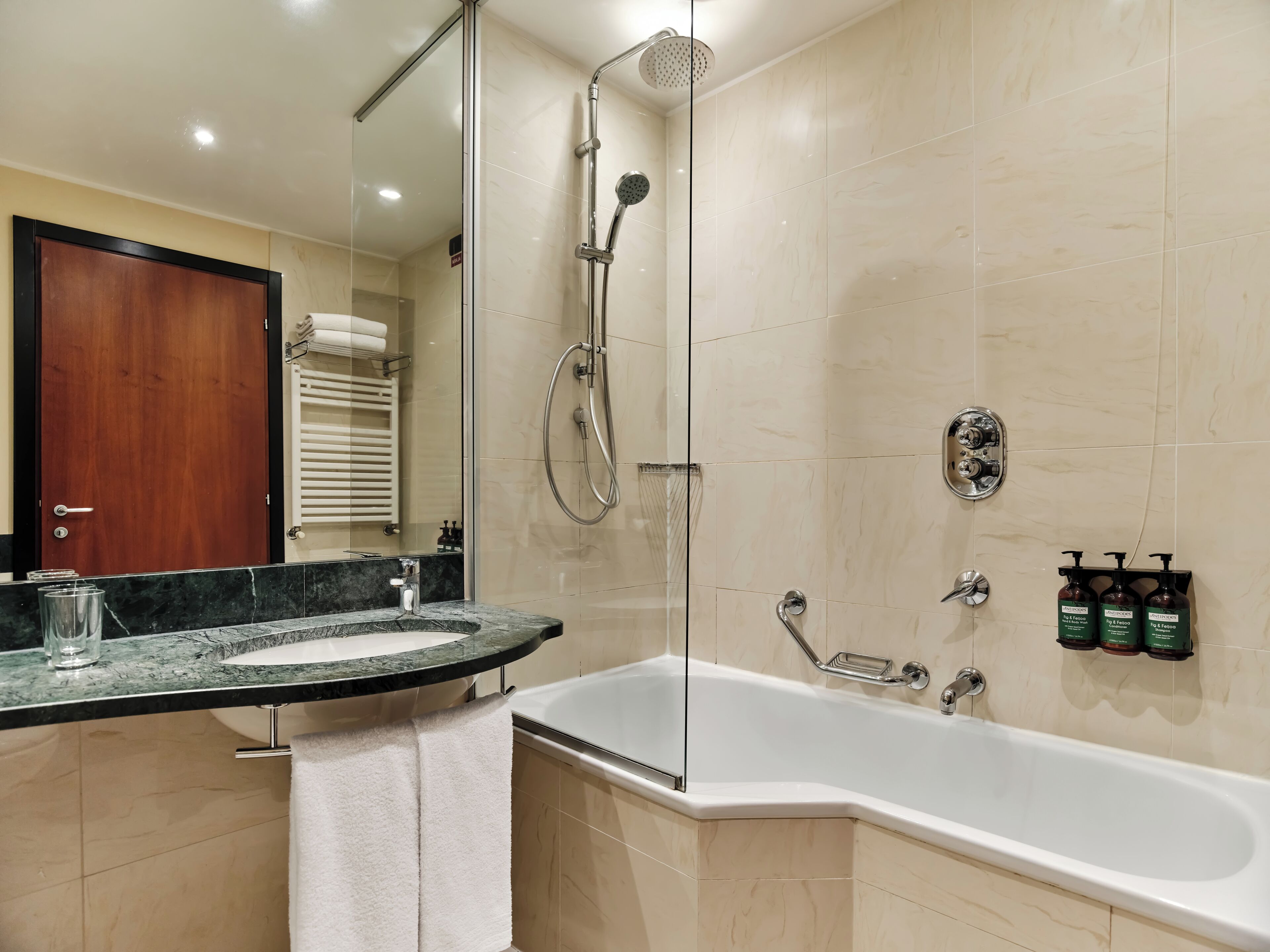 Un baño moderno con ducha de vidrio, bañera independiente y encimera de mármol con una toalla.
