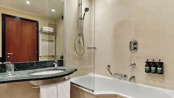 Un baño moderno con ducha de vidrio, bañera independiente y encimera de mármol con una toalla.