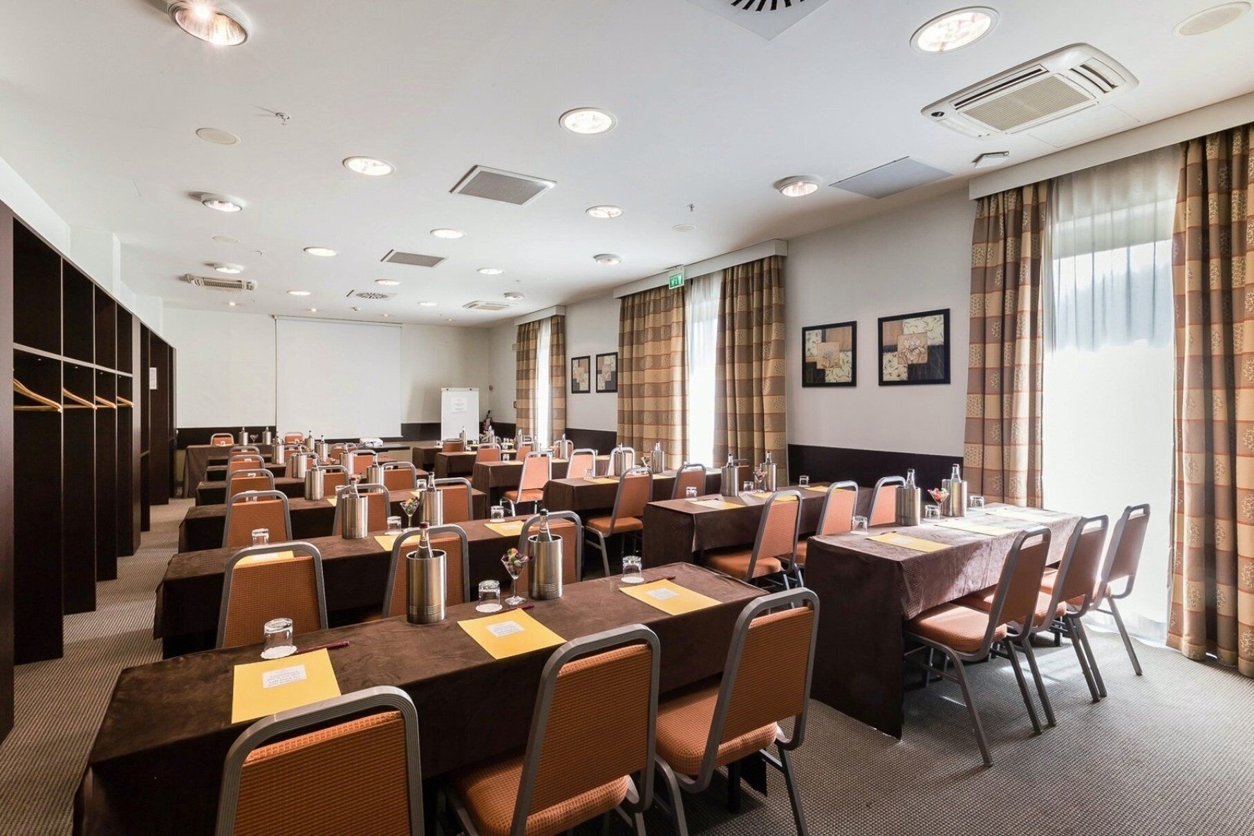 A conference room with multiple tables and chairs, equipped with nameplates and water bottles.