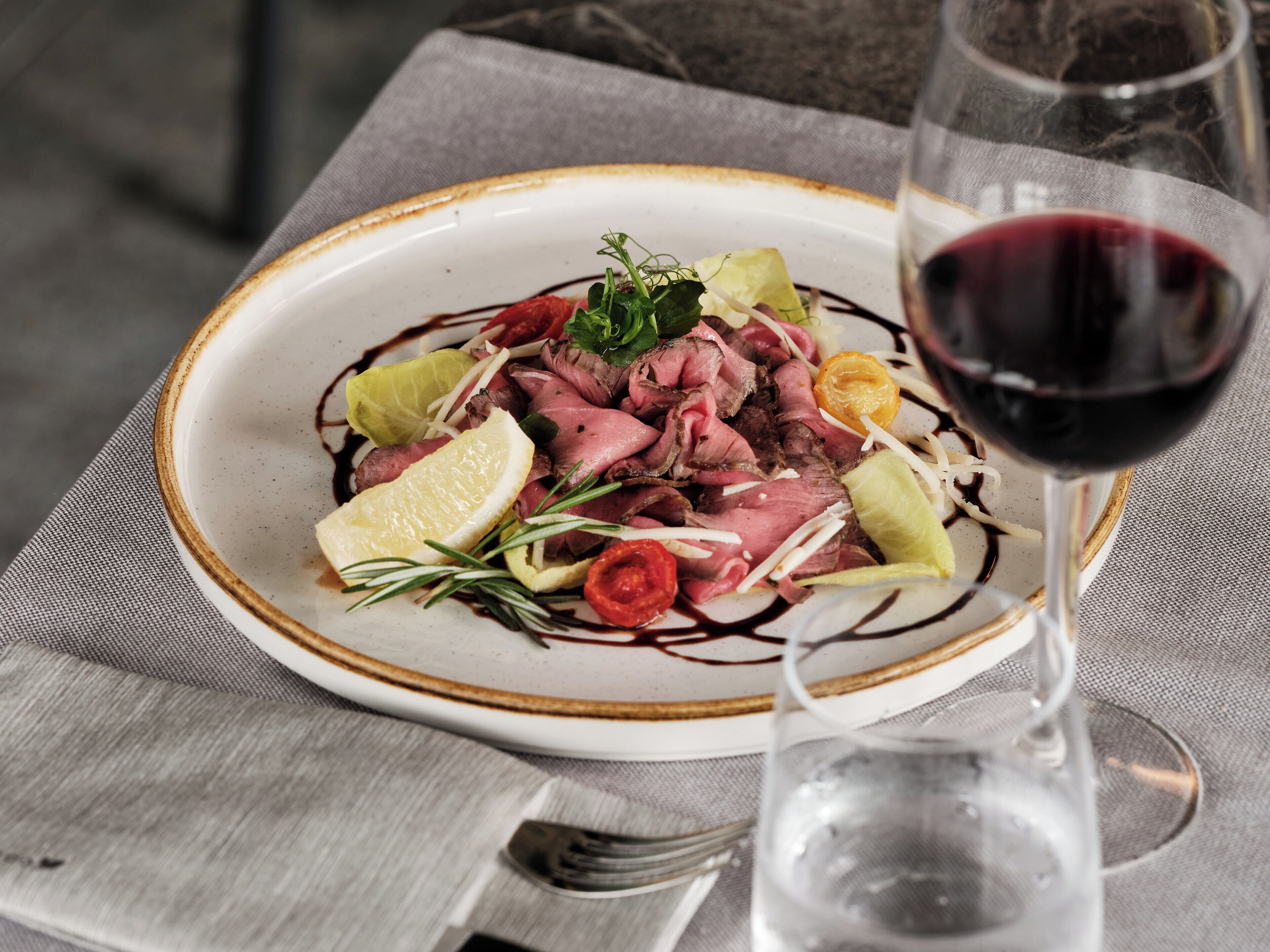 A plate of food with a glass of red wine on a table.